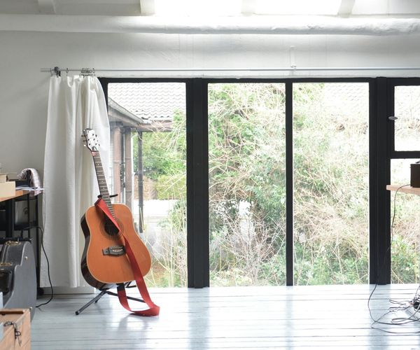 Interior of a bright, clean, and modern fitness studio with wooden floors and large windows.